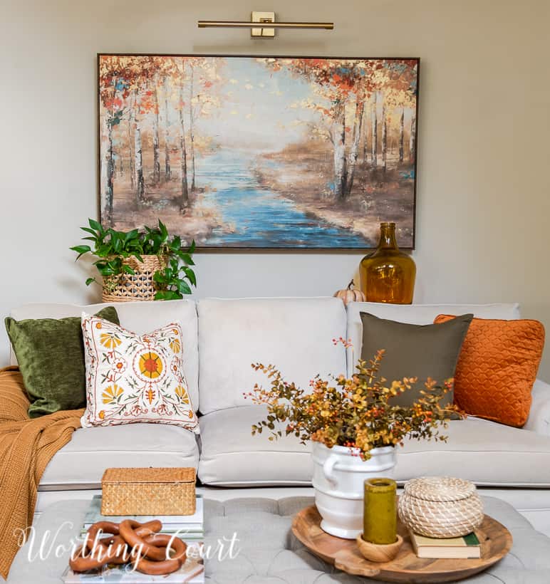 neutral colored couch filled with fall pillows with an upholstered coffee table in front