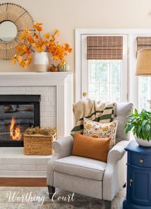 gray arm chair and side table beside white fireplace with fall decor on the mantel and hearth