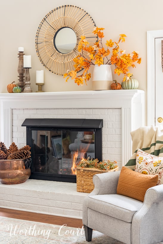 white fireplace with fall decor on the mantel and hearth