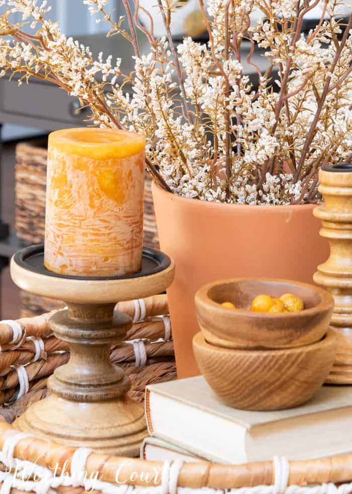 fall vignette with wood candlesticks and bowls and terra cotta planter filled with faux stems