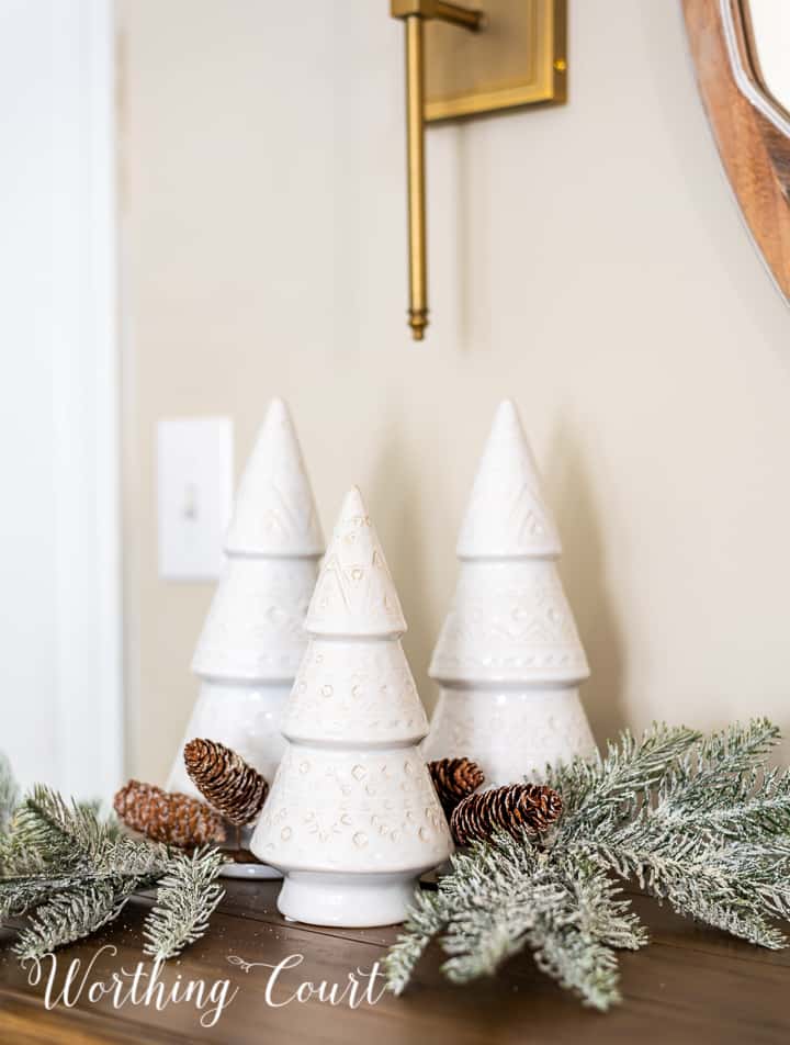 trio of different sized white modern style ceramic Christmas trees and a pair of faux greenery picks