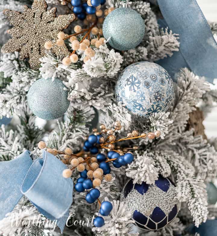 Blue and champagne gold ornaments on a flocked Christmas tree