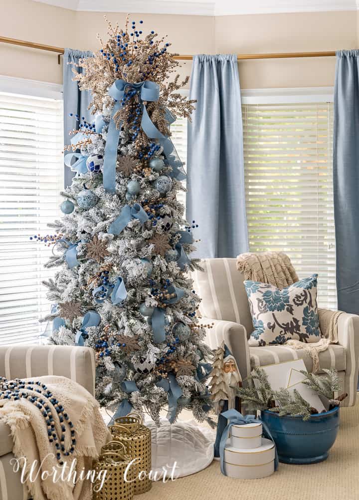 Flocked Christmas tree with blue and gold ornaments between two chairs