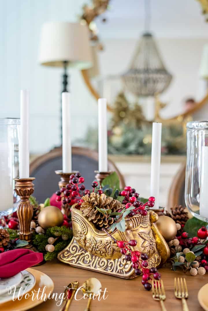 Christmas centerpiece with a gold sleigh, gold candlesticks and burgundy and gold accents