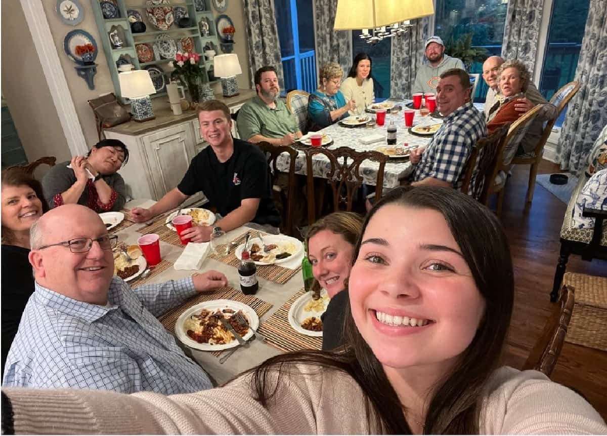 group of people sitting around two tables in a dining room during a meal