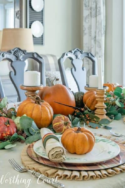 Thanksgiving table centerpiece made with orange pumpkins and green eucalyptus leaves