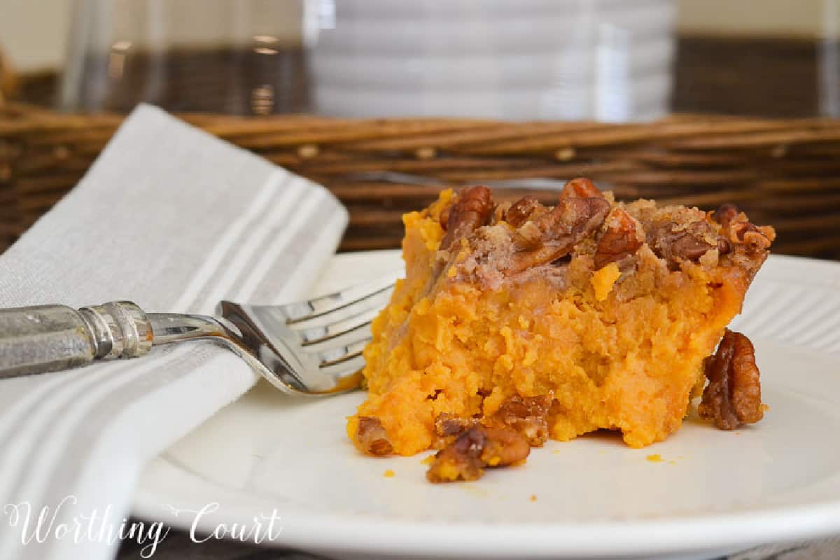a piece of sweet potato casserole on a white plate with a silver fork