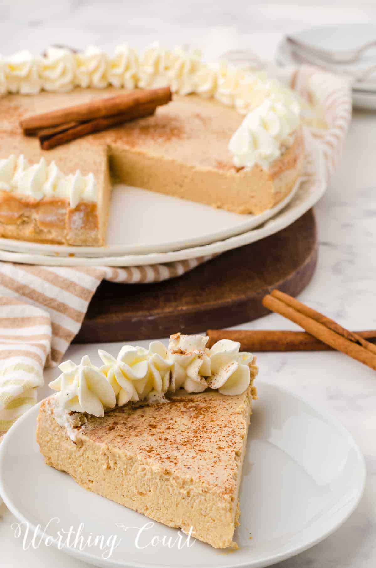 slice of ginger cheesecake on a white plate with rest of cheesecake in the background