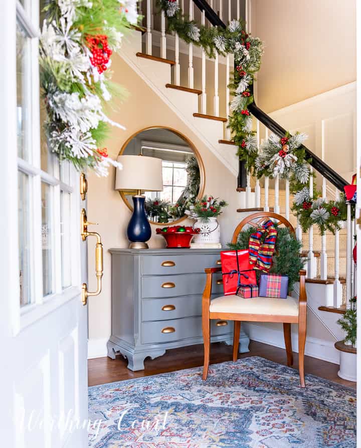 chair in foyer in front of handrail with Christmas garland with red and blue decor