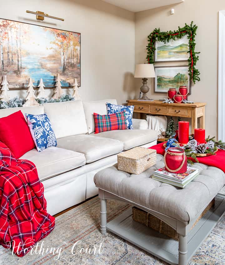 upholstered coffee table in front of neutral couch with red and blue pillows and throw blankets