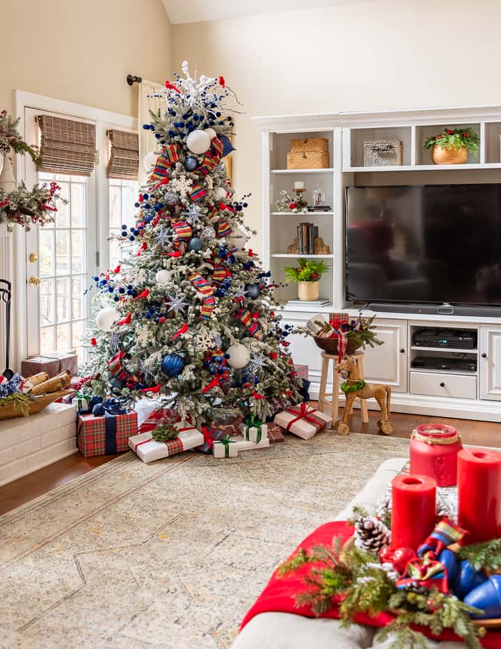 Christmas tree with red and blue decorations beside white entertainment center