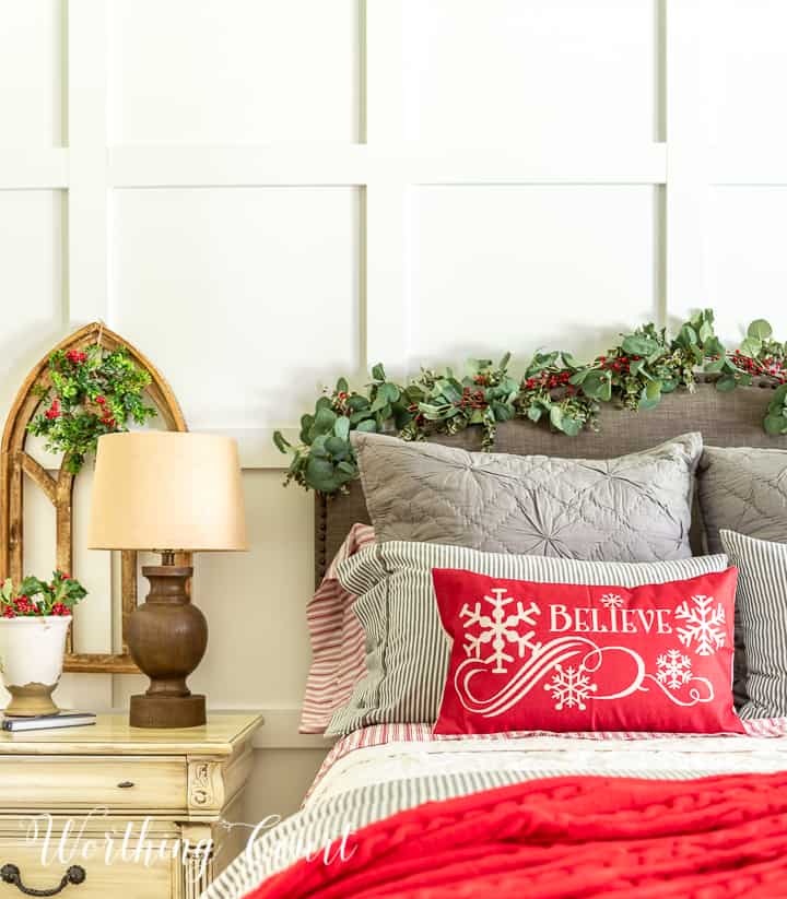 bed in front of white wall with gray, red and white bedding