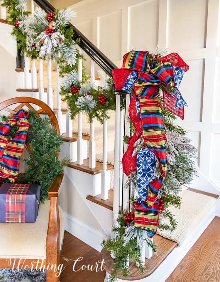Christmas garland on stair rail with blue, red and green striped ribbon