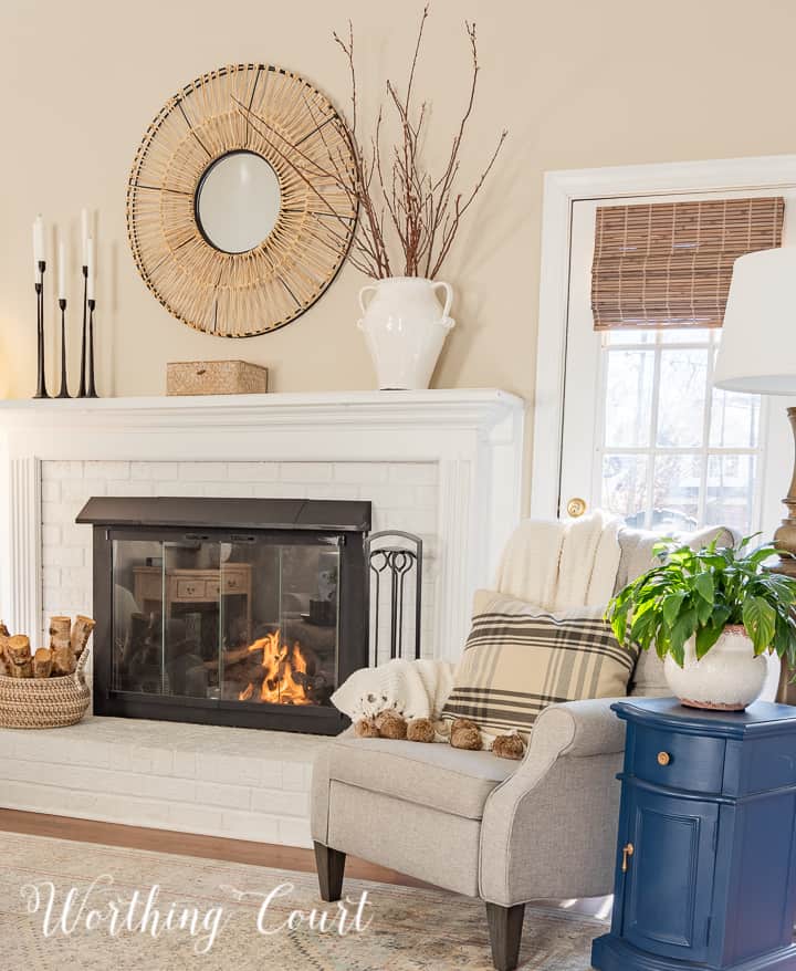 light gray recliner and blue side table beside white brick fireplace with winter decor