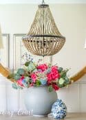 faux flower arrangement in front of a round mirror above a dining room sideboard