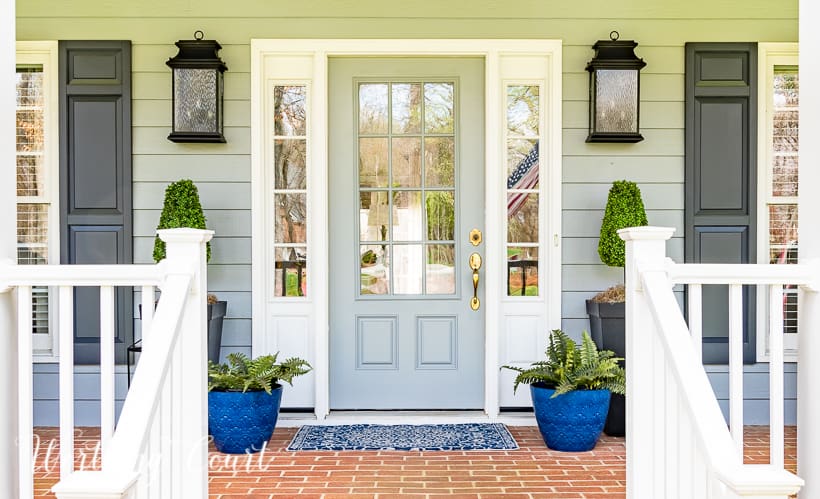 gray front door and sidelights flanked by blue planters