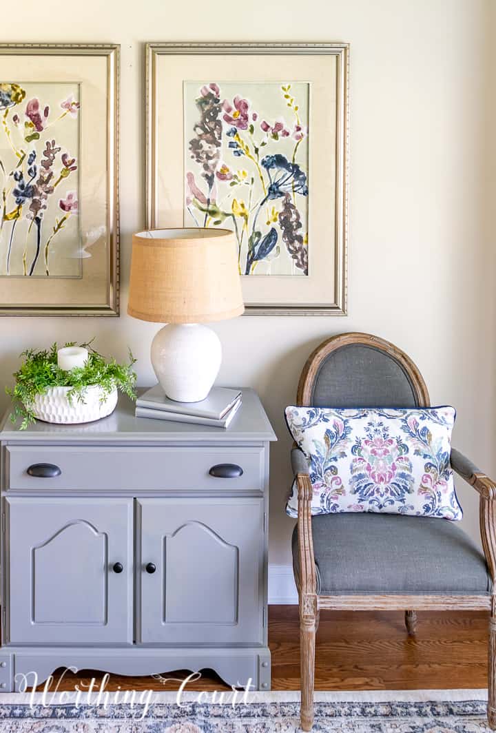 gray dining chair beside gray chest with multi colored artwork