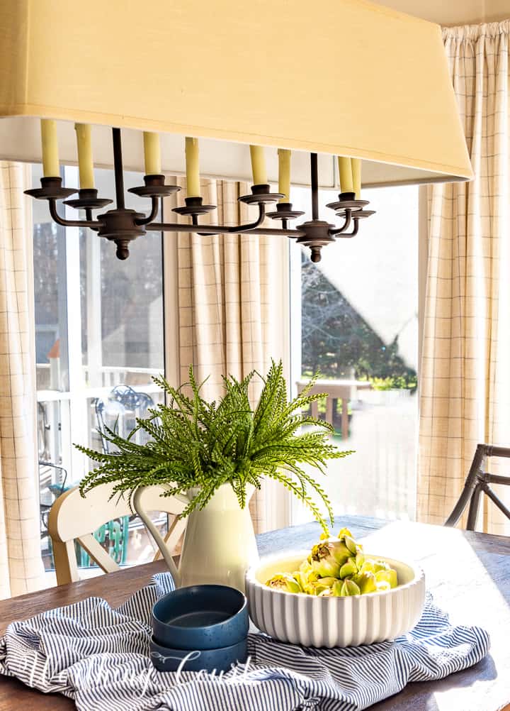 spring centerpiece with blue and white accessories and faux greenery on a dining table