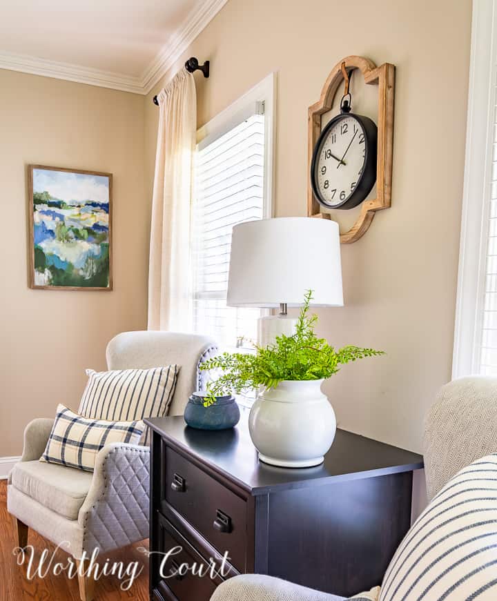 arm chairs flanking black file cabinet with blue and white pillows and artwork