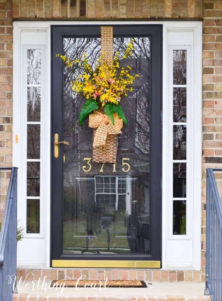 hanging basket filled with yellow flowers and greenery on a black front door