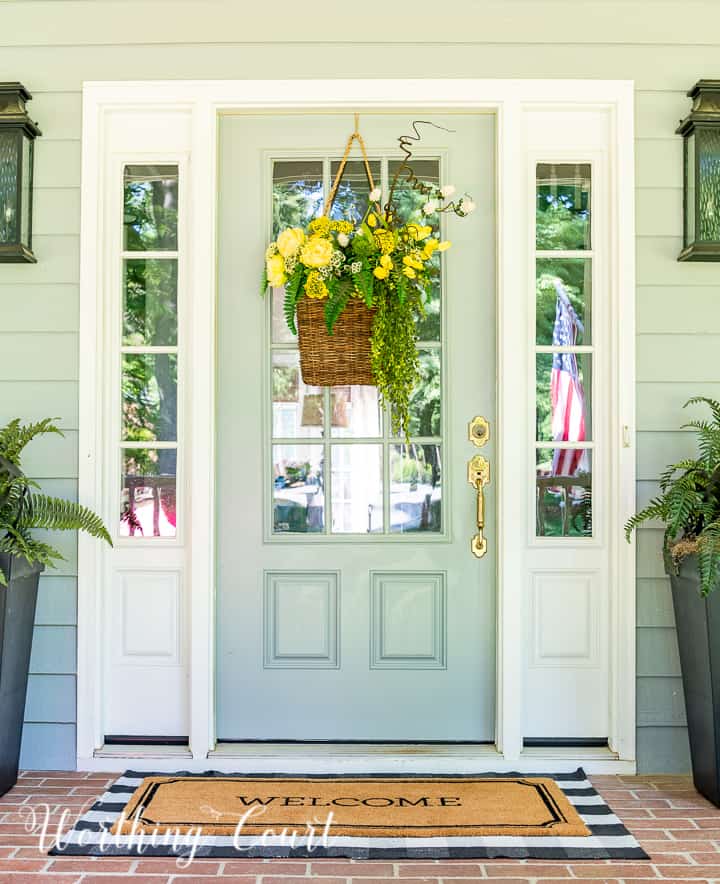 hanging basket filled with yellow flowers and greenery on a gray front door