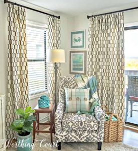accent arm chair in corner between to windows with draperies