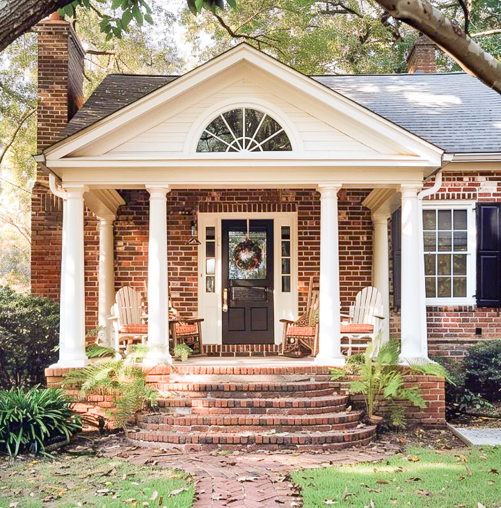 small front porch on a red brick house filled with plants