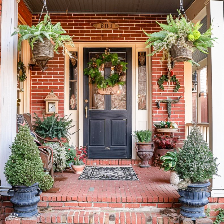 small front porch on a red brick house filled with plants