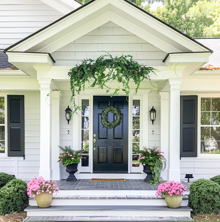 small front porch on a white house with greenery and flowers