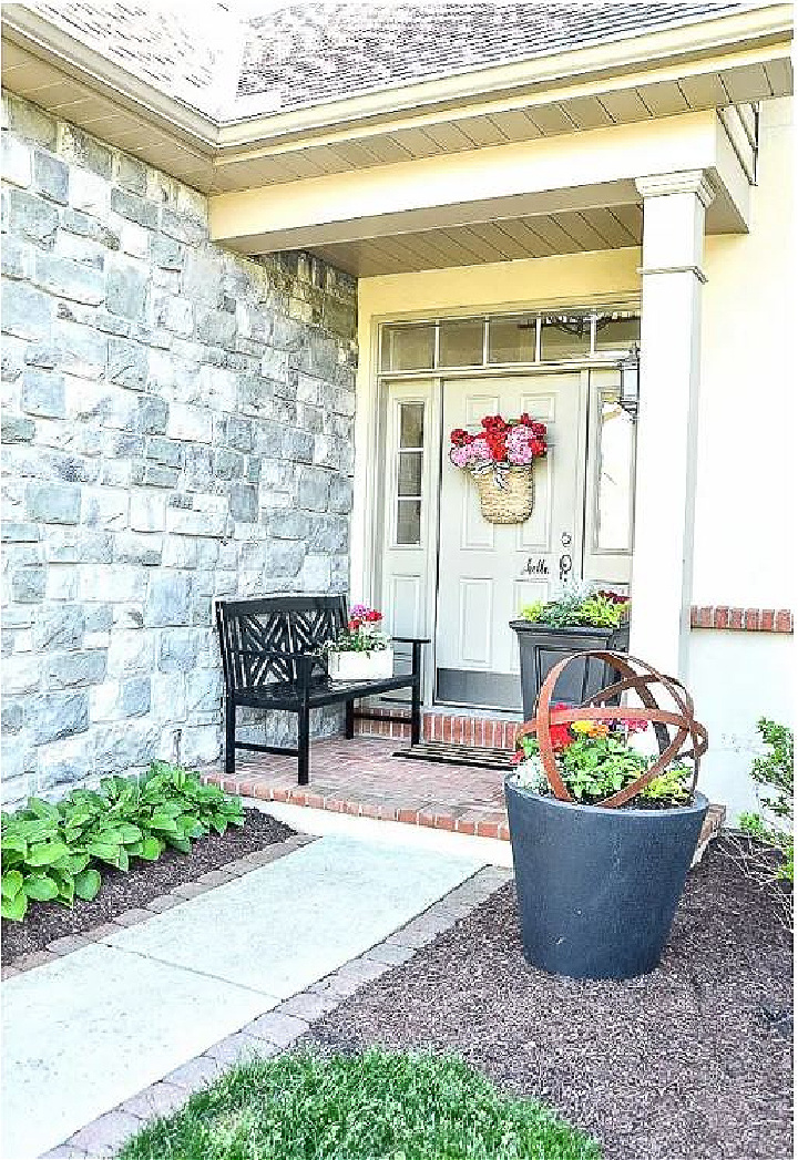 small front porch with a bench and basket of flowers hanging on the front door