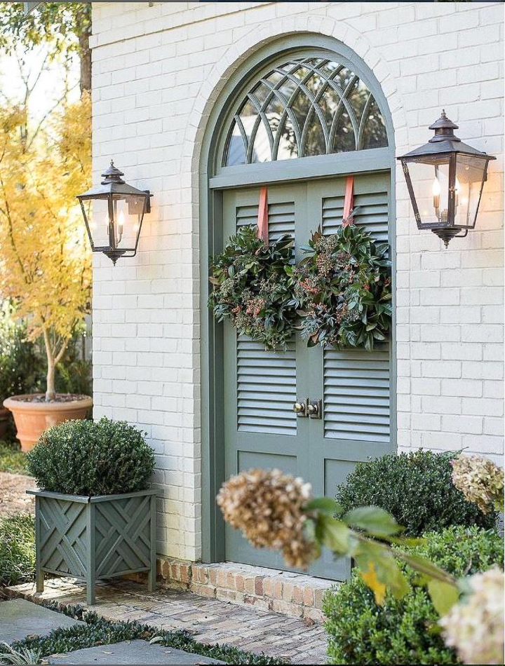 small front porch with a gray door with wreaths and greenery