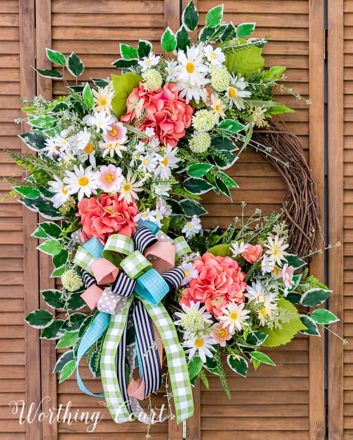 A wreath made with colorful flowers and ribbons hanging on the wall