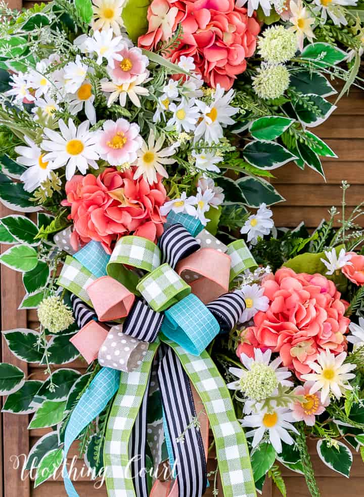 A wreath made with colorful flowers and ribbons hanging on the wall