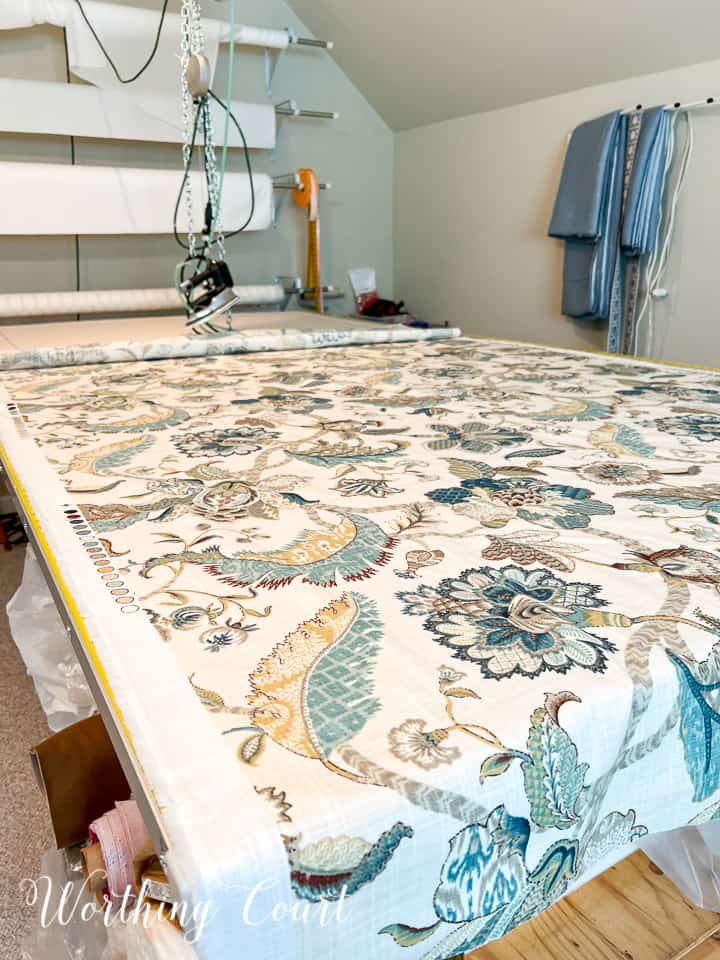 blue and white fabric spread out on a cutting table in a sewing room