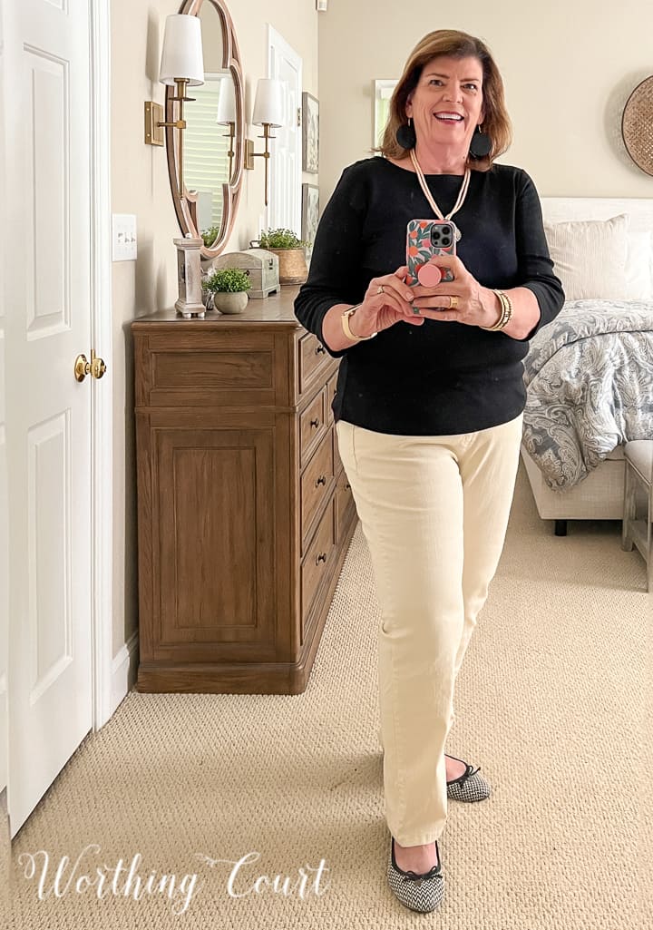 woman wearing black top with ivory pants taking selfie