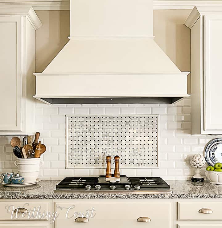 kitchen with white cabinets and large vent hood over a cooktop