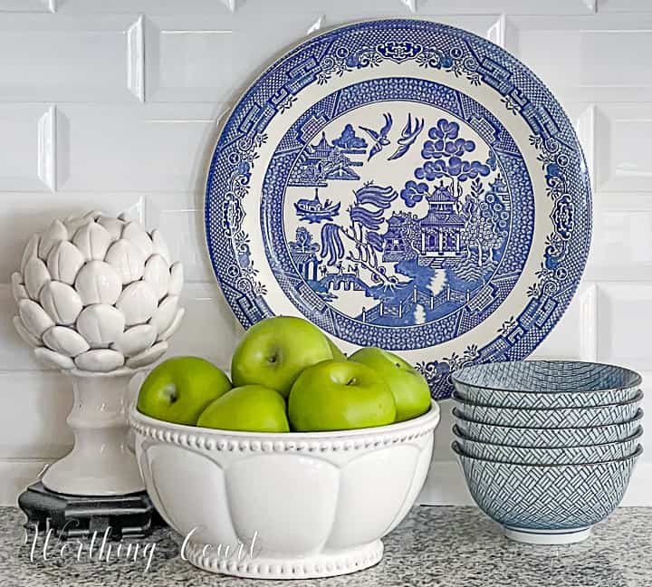 blue and white vignette with green apples in a bowl in a kitchen counter