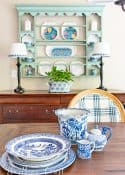 blue and white dishes on a table in front of a plate rack above a sideboard