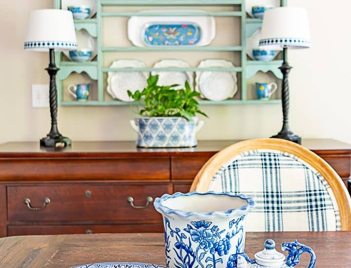 blue and white dishes on a table in front of a plate rack above a sideboard