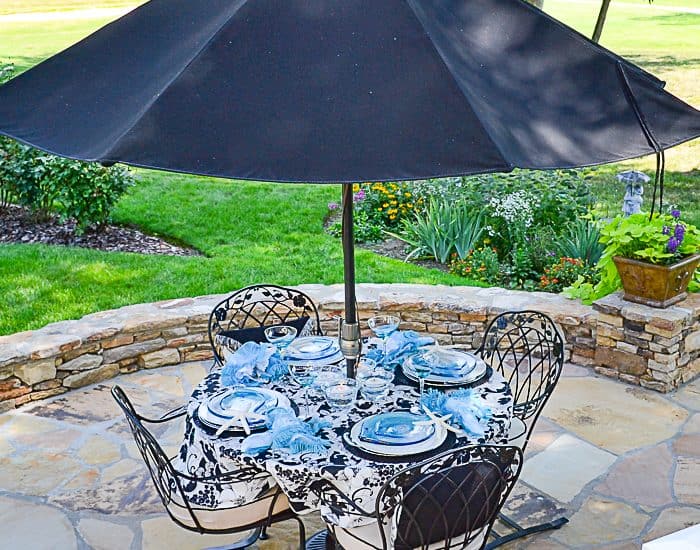 outdoor table with black umbrella on a flagstone patio