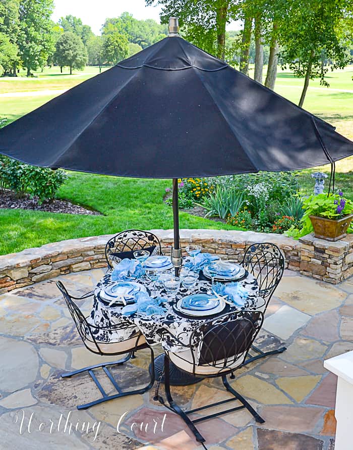 outdoor table with black umbrella on a flagstone patio