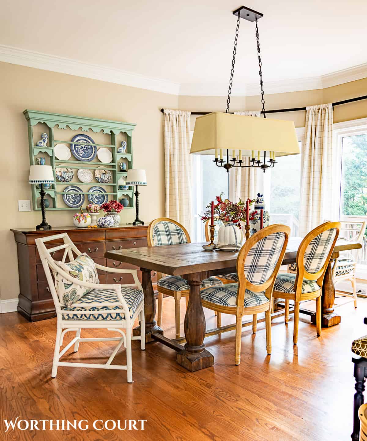 fall decorations in a breakfast room with table, chairs, sideboard and plate rack with a large bay window