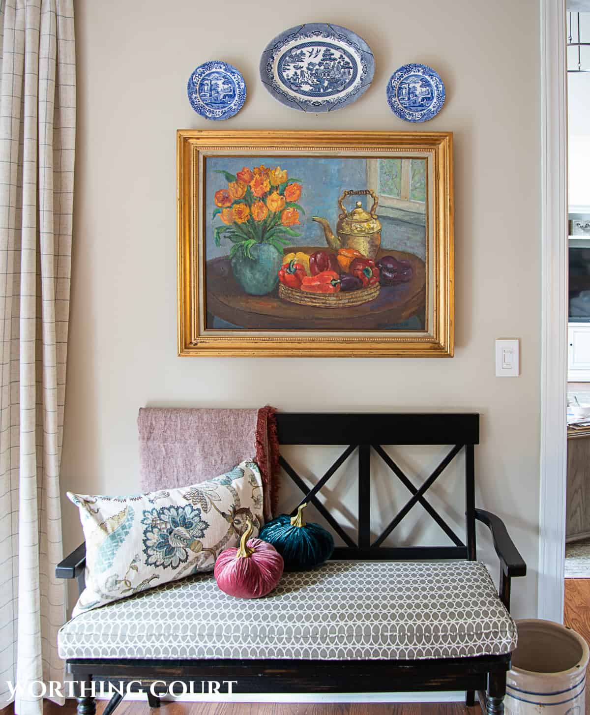 fall breakfast room and kitchen decor with an oil painting and plates hanging above a black bench