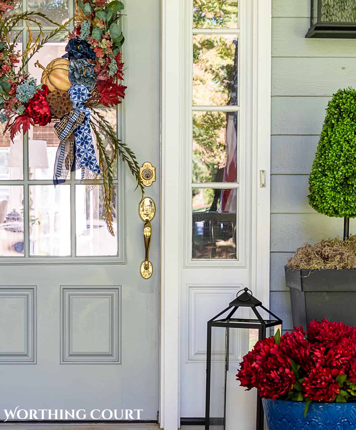 blue and burgundy fall front porch decor featuring a diy wreath, topiaries and faux mums
