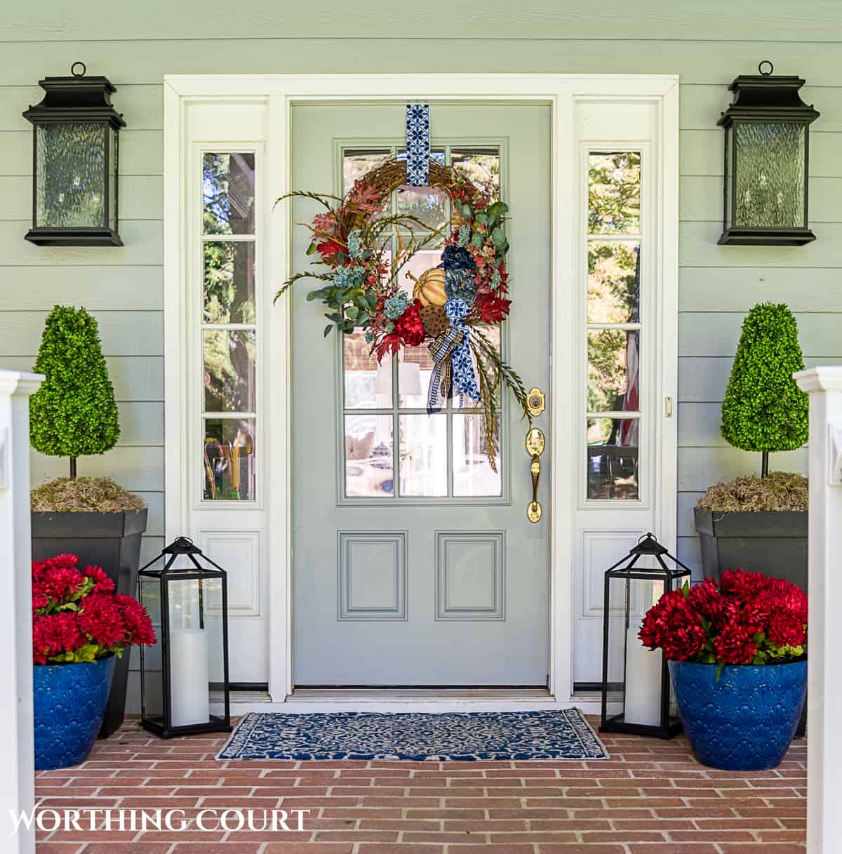 blue and burgundy fall front porch decor featuring a diy wreath, topiaries and faux mums