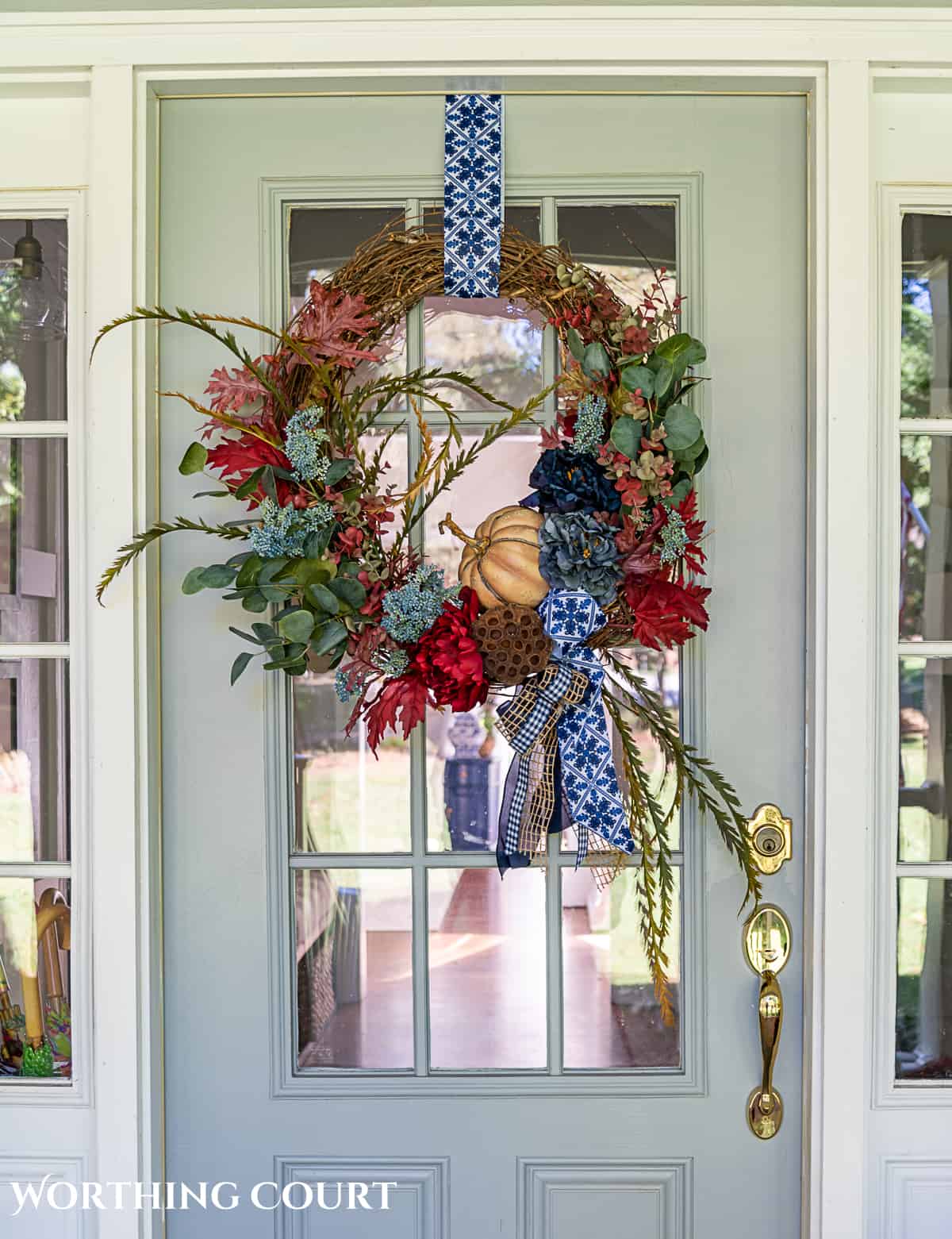 blue and burgundy fall front porch decor featuring a diy wreath, topiaries and faux mums