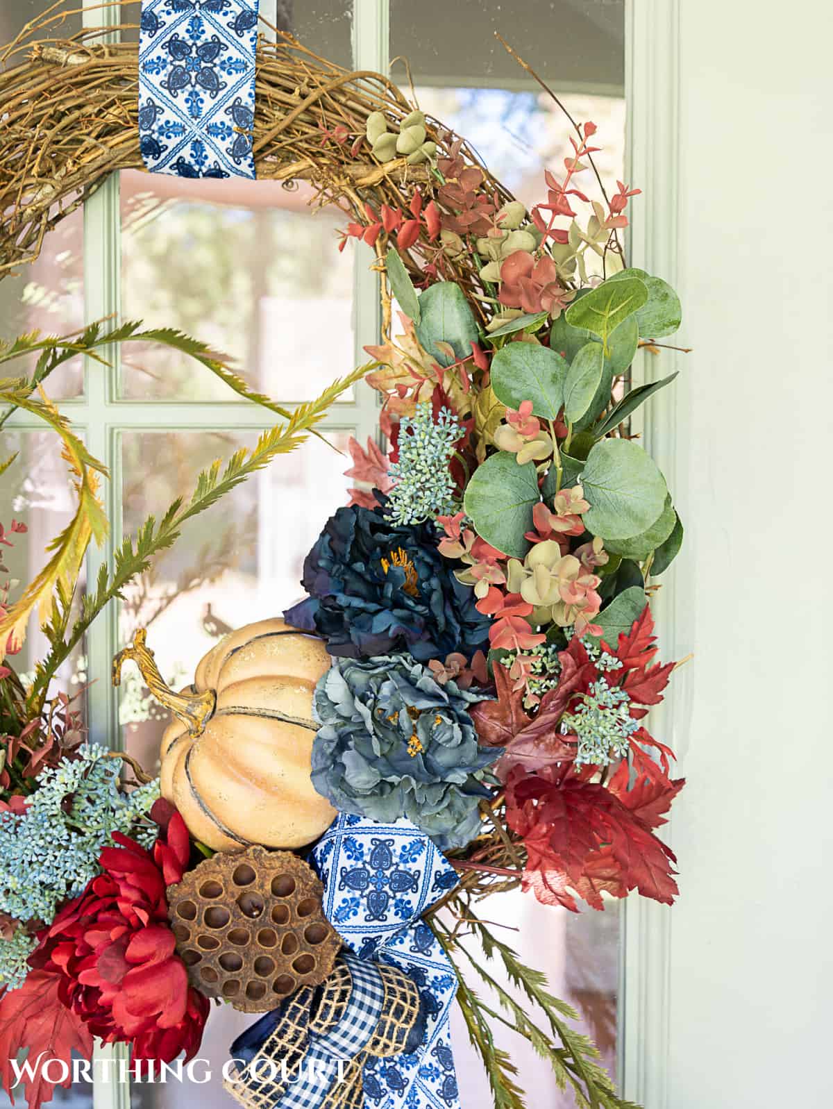 blue and burgundy fall front porch decor featuring a diy wreath, topiaries and faux mums