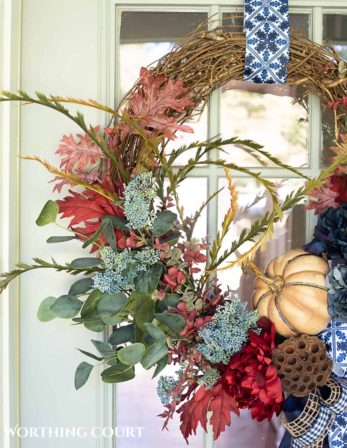 blue and burgundy fall front porch decor featuring a diy wreath, topiaries and faux mums