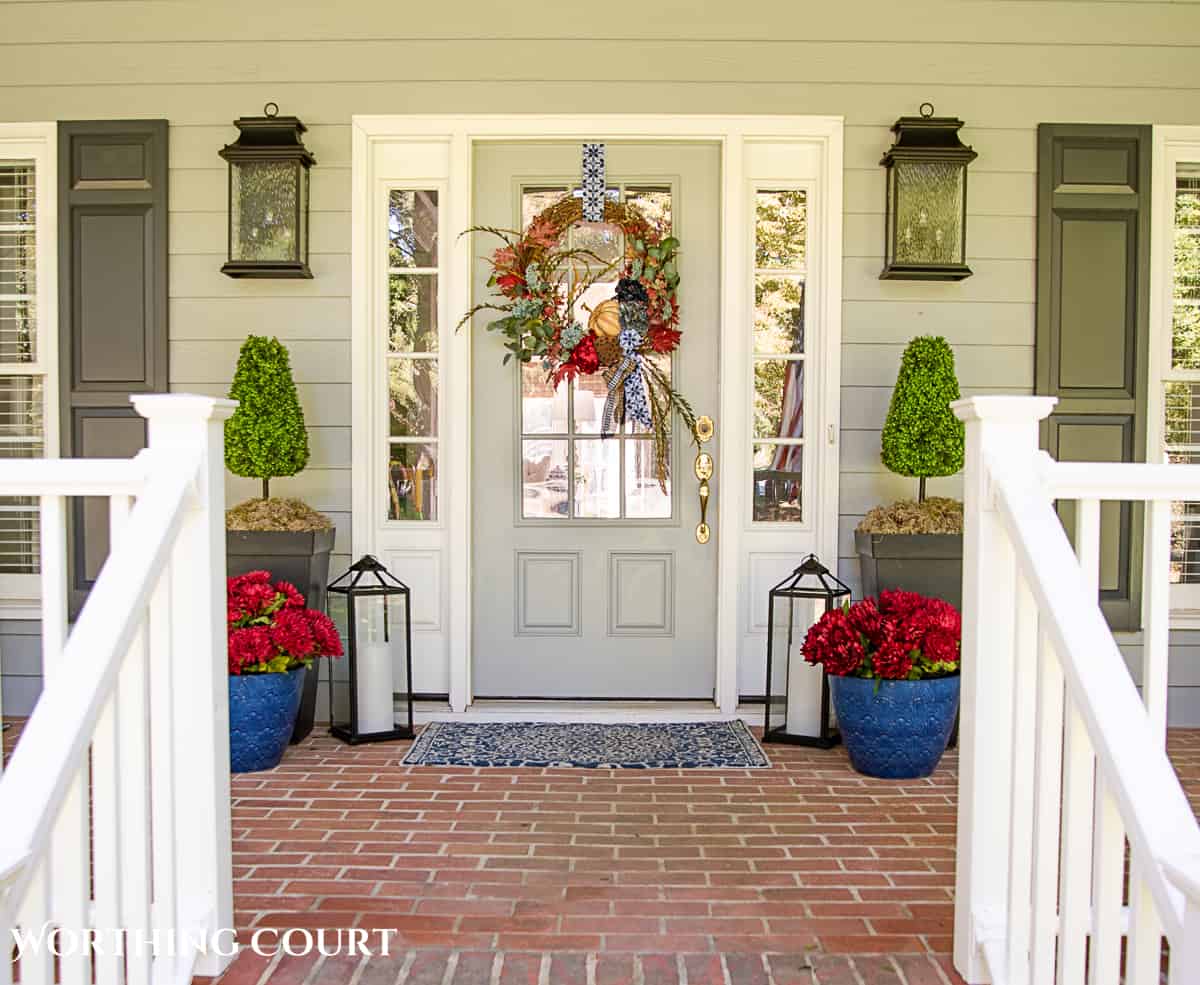 blue and burgundy fall front porch decor featuring a diy wreath, topiaries and faux mums