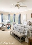 bay window with blue drapery panels and arm chairs in a master bedroom